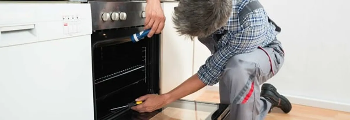 Oven repair technician inspecting and servicing an electric oven in Cleveland, OH