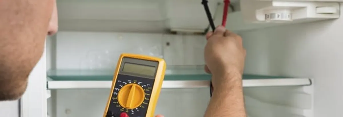 Refrigerator repair technician testing electrical components with a multimeter in Cleveland, OH
