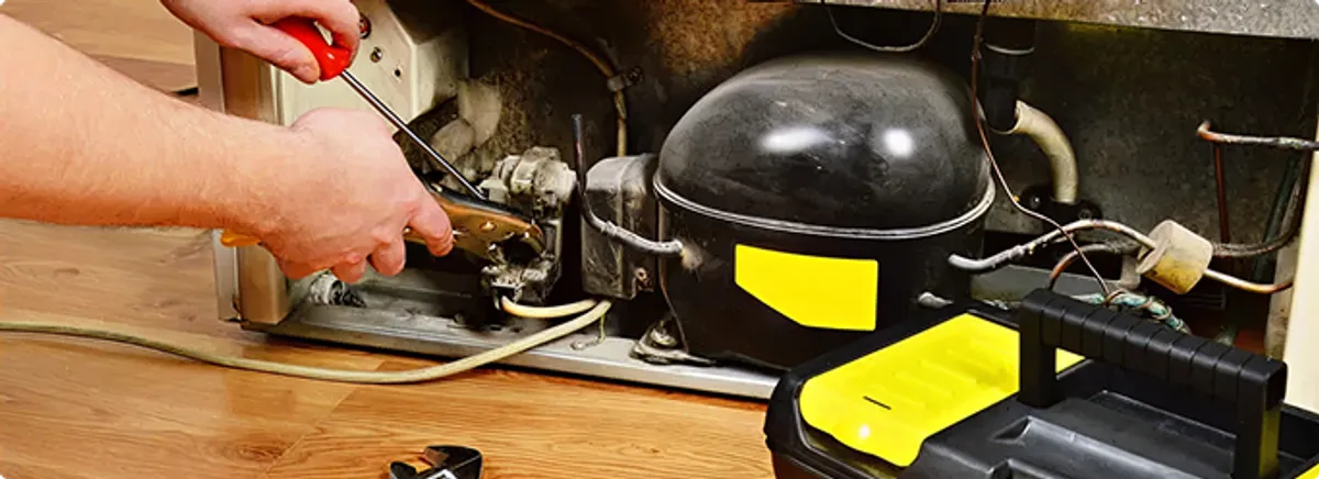 Refrigerator repair technician fixing the compressor and wiring in Cleveland, OH
